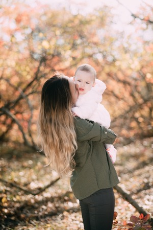 Charming child in the arms of his mother in the autumn forestの写真素材