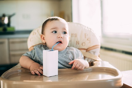 A child, a girl drinking juice or milk with a tube of white packaging there is a place for the inscriptionの写真素材