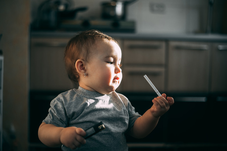 A child, a girl with a cigarette and a lighter in her hands, tries interestedの写真素材