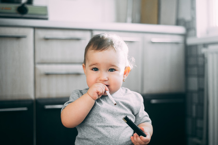 A child, a girl with a cigarette and a lighter in her hands, tries interestedの写真素材