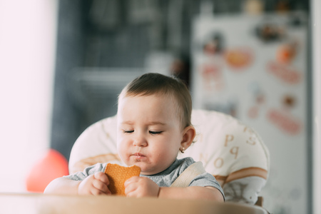 little girl in a high chair eating cookies