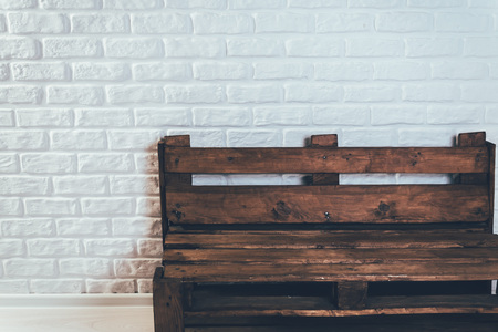 Wooden bench of flying against a white brick wall