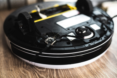 the back of the robot vacuum cleaner clogged with debris and dustの写真素材