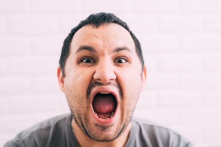 Portrait of young man screaming with beard in grey t-shirtの写真素材