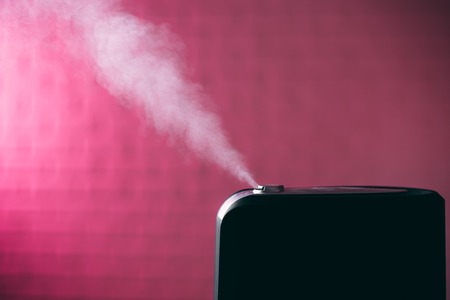 black humidifier on pink background with white steamの写真素材