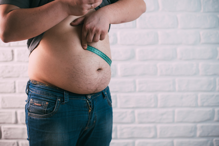 fat man check out his body fat with measuring tape for white or obesity background