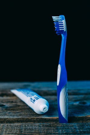 Toothbrush with toothpaste on wooden table background with space for text blue lightの写真素材