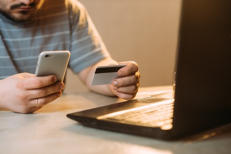 Cropped picture of man with credit card white pattern and phone