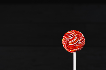red, round colored Lollipop on black backgroundの写真素材