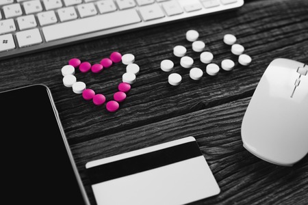 On a wooden table Tablets in the form of heart and pulse and Credit card, keyboard, mouseの写真素材