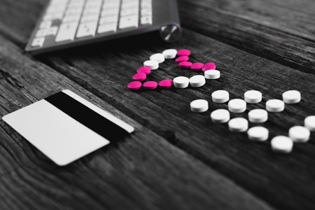 On a wooden table Tablets in the form of heart and pulse and Credit card, keyboard, mouseの写真素材