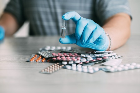 Doctor in blue gloves is holding a vial of demonstratingの写真素材