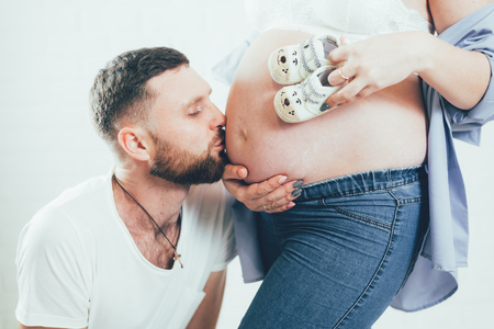 Husband kiss on the belly of the motherの写真素材