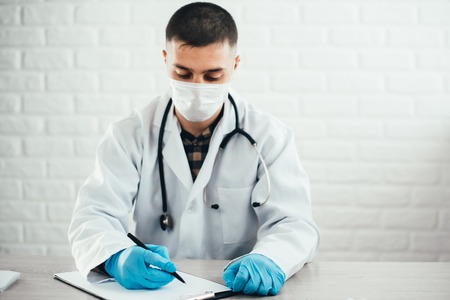 Doctor writing on a notepad in medical officeの写真素材