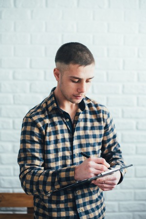 A man in a plaid shirt writes to the clipboard