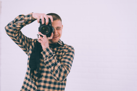 A man in a plaid shirt with a camera in his handsの写真素材