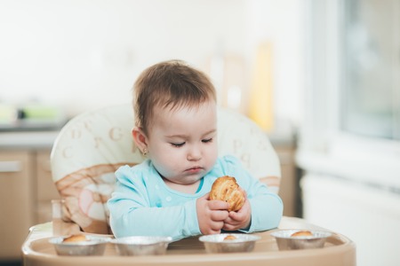 the little girl in the highchair in the hands Krapina, like muffins and croissants trend 2019の写真素材