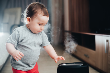Little baby looks at the humidifier. Moisture in the house conceptの写真素材