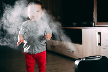 Little baby looks at the humidifier. Moisture in the house conceptの写真素材