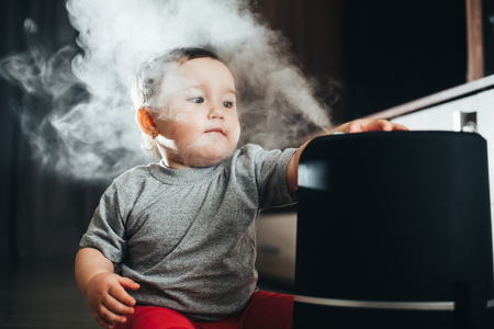 Little baby looks at the humidifier. Moisture in the house concept