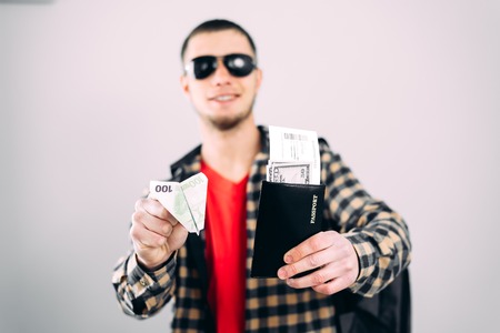 a man in sunglasses with a passport and an origami plane ticket from a Euro billの写真素材
