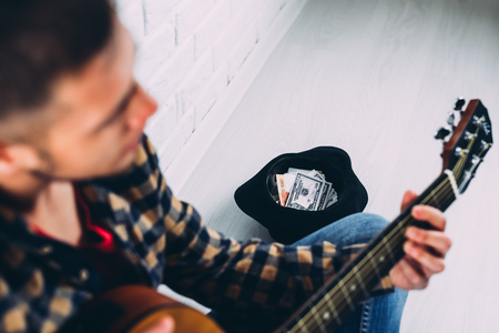 Handsome mature man in casual clothes is smiling while playing guitar at homeの写真素材