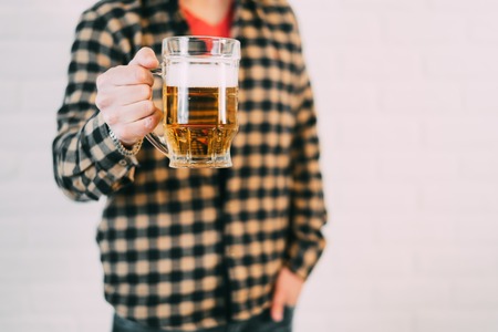young guy in a shirt with a glass of beer in his handの写真素材