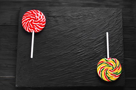 red and yellow round lollipops on black background with textureの写真素材