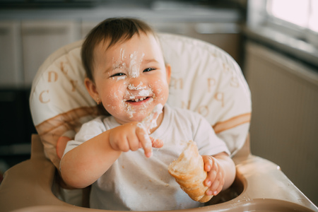 baby in the kitchen eagerly eating the delicious cream horns, filled with a vanilla creamの写真素材