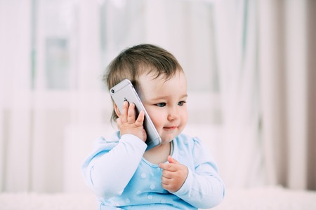 A little girl talking on a smartphone smiling and happy