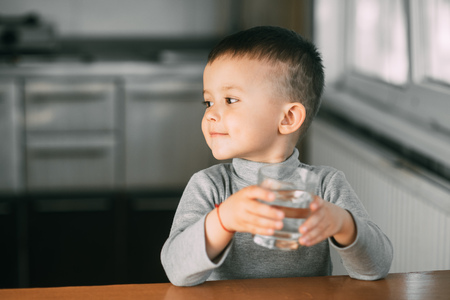 Portrait of a boy drinking a glass of water,happy in the kitchenの写真素材