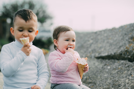 Little kids brother and sister eating ice cream outdoors in the villageの写真素材