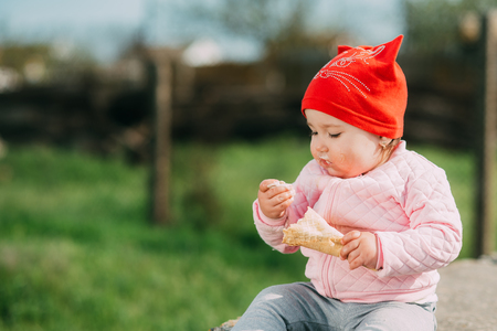 Little girl outdoors in the village eating ice cream very greedilyの写真素材