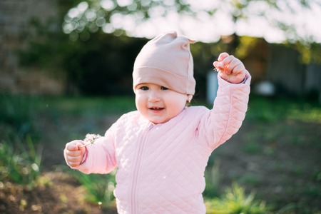 a little girl with a dandelion in her hands having fun