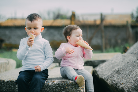 Little kids brother and sister eating ice cream outdoors in the villageの写真素材