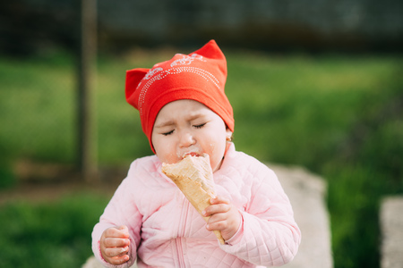 Little girl outdoors in the village eating ice cream very greedilyの写真素材