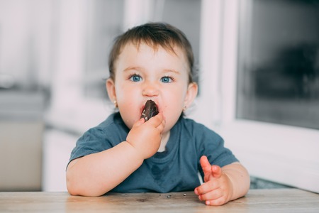 A little girl in the kitchen eating marshmallows in chocolate or chocolate chip cookies is very tastyの写真素材