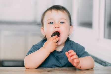 A little girl in the kitchen eating marshmallows in chocolate or chocolate chip cookies is very tastyの写真素材