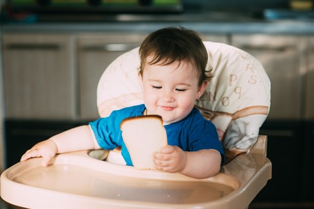 Baby girl is very greedy eating a piece of white bread, hungry and happyの写真素材