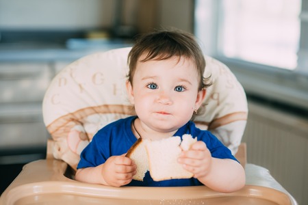 Baby girl is very greedy eating a piece of white bread, hungry and happyの写真素材