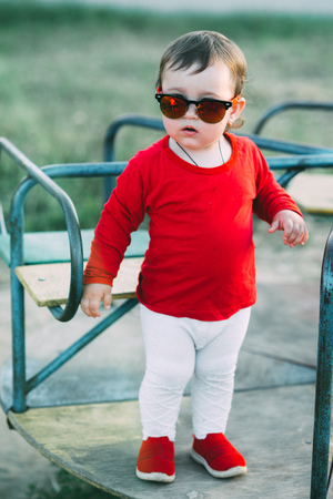 charming little girl in red t-shirt and red glasses, outdoorsの写真素材