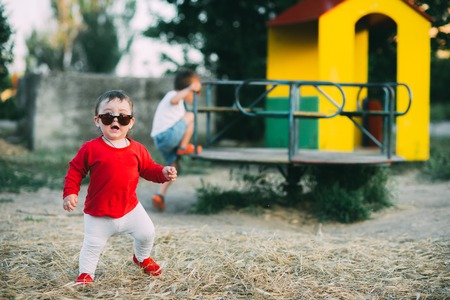 charming little girl in red t-shirt and red glasses, outdoorsの写真素材