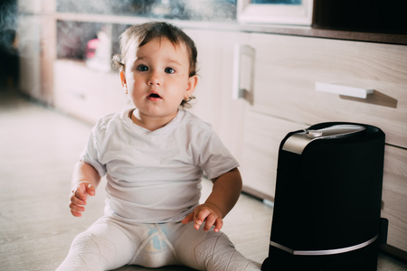 The baby looks at the humidifier. The concept of humidity in the home and healthの写真素材