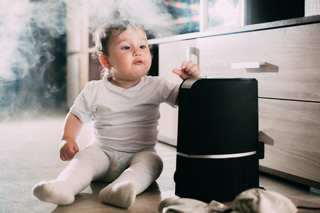 The baby looks at the humidifier. The concept of humidity in the home and healthの写真素材