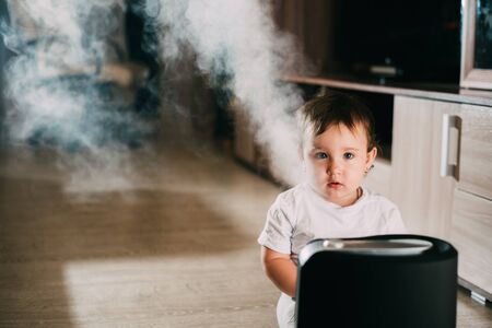 The baby looks at the humidifier. The concept of humidity in the home and healthの写真素材