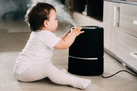 The baby looks at the humidifier. The concept of humidity in the home and healthの写真素材