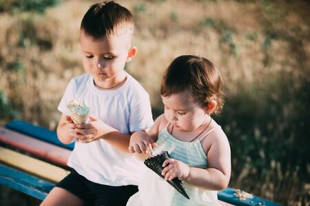 Brother and sister eating ice cream on the bench in the Playground