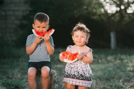 Funny kids eating watermelon, the sun is shining in the back very cuteの写真素材