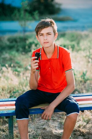 teen on a bench eating ice cream in a red t-shirt in the summerの写真素材