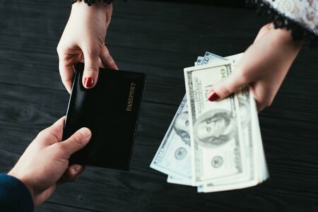 On a black wooden background, a top view of a hand handing over a passport and money loan approval concept.の写真素材